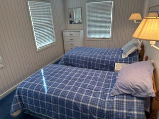 A bedroom with two twin beds and a lamp.