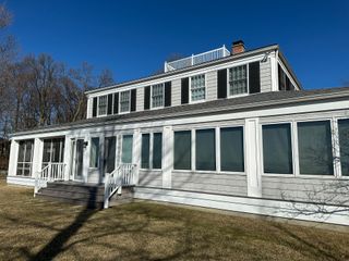 A large white house with a lot of windows and a porch on a sunny day.