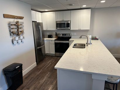 A kitchen with white cabinets , stainless steel appliances and a large island.