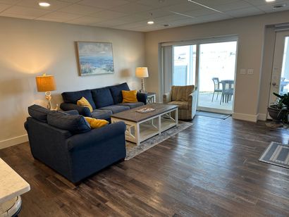 A living room with a couch , chair , coffee table and sliding glass doors.