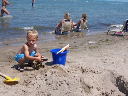 A young boy is playing in the sand on the beach