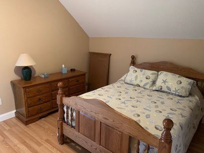 A bedroom with a bed , dresser and lamp