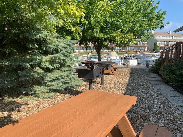 A wooden picnic table with a grill in the background