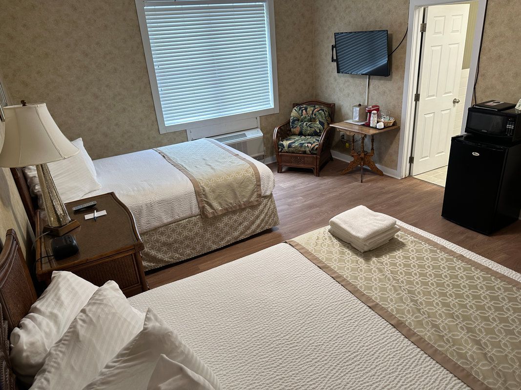 A hotel room with two beds , a chair and a television.