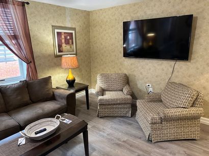 A living room with a couch , chair , coffee table and television.