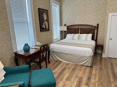 A bedroom with a bed , chair , desk and ottoman.