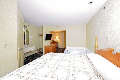 A hotel room with a king size bed and a jacuzzi tub.