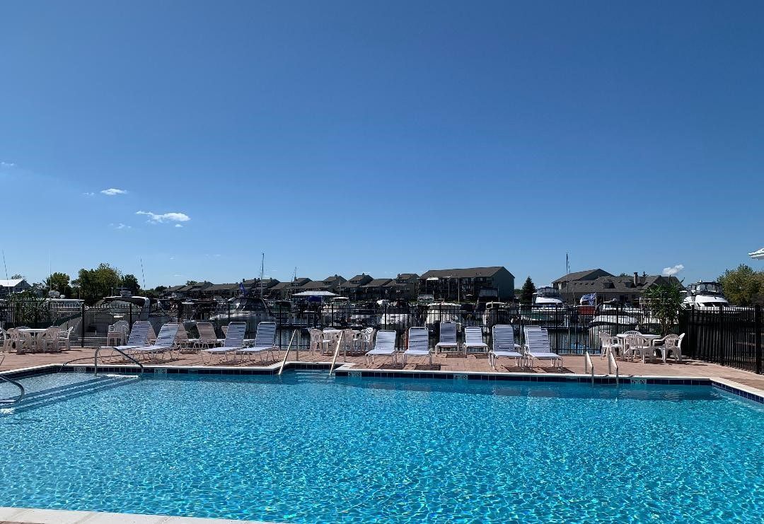 A large swimming pool surrounded by chairs and tables on a sunny day.