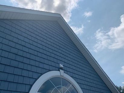 A blue house with a white window and a blue sky in the background