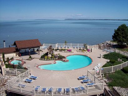 A large swimming pool surrounded by chairs and a gazebo overlooking the ocean