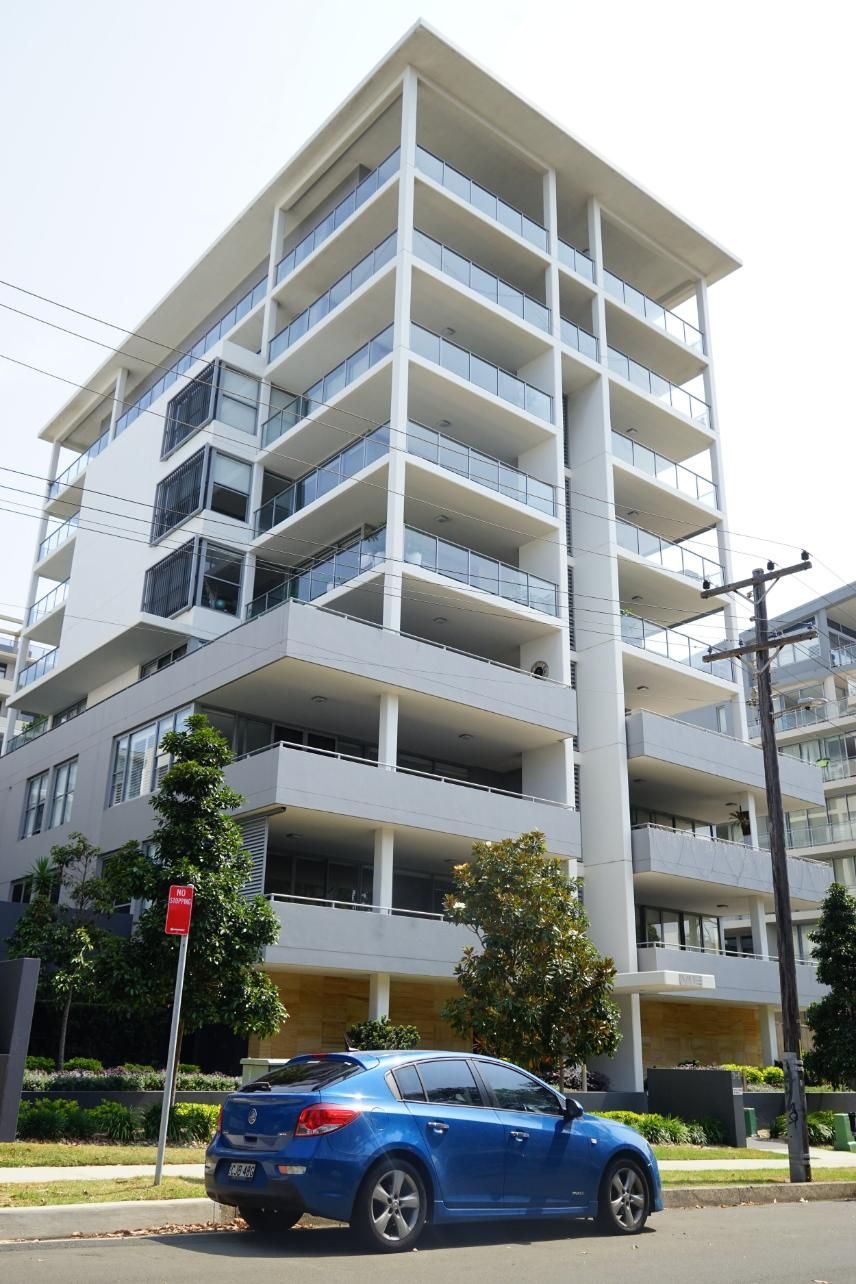 A Blue Car Is Parked In Front Of A Tall Building — Rendering By Yilmaz P/L In Wollongong, NSW