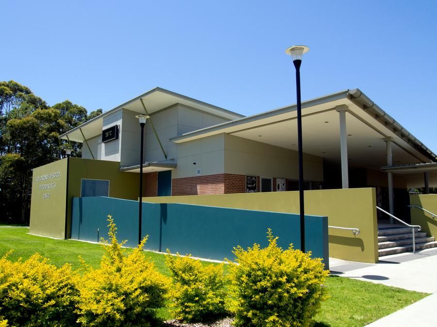 A Large Building With A Green Fence And Yellow Bushes In Front Of It — Rendering By Yilmaz P/L In Wollongong, NSW