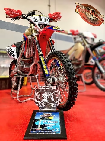 Custom red and chrome dirt bike on a display stand at an indoor show