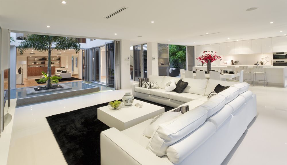 A Living Room With a White Sectional Couch and a Black Rug — Suncoast Kitchens In Noosa, QLD