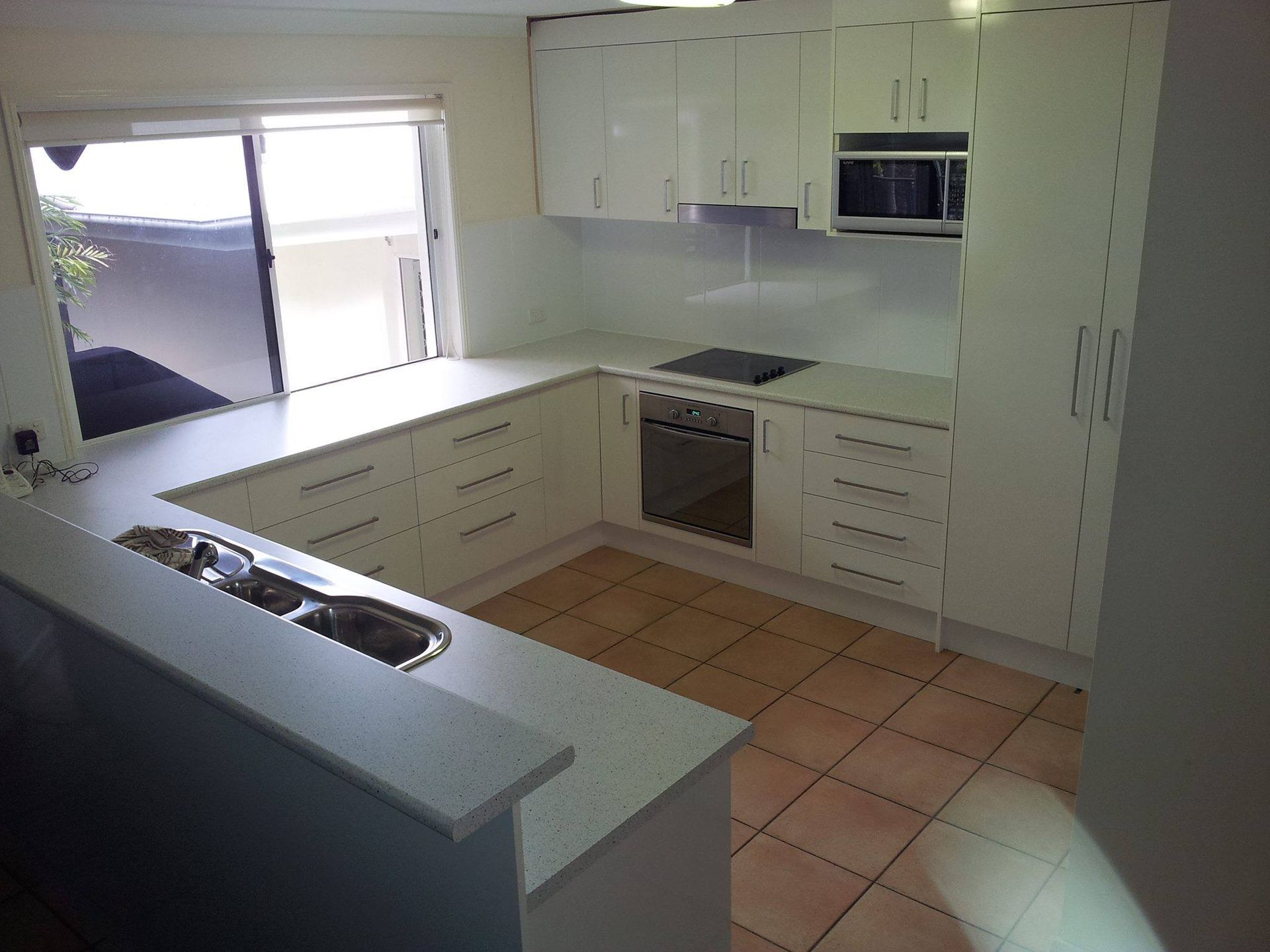 A Kitchen With White Cabinets and a Stove Top Oven — Suncoast Kitchens In Caboolture, QLD