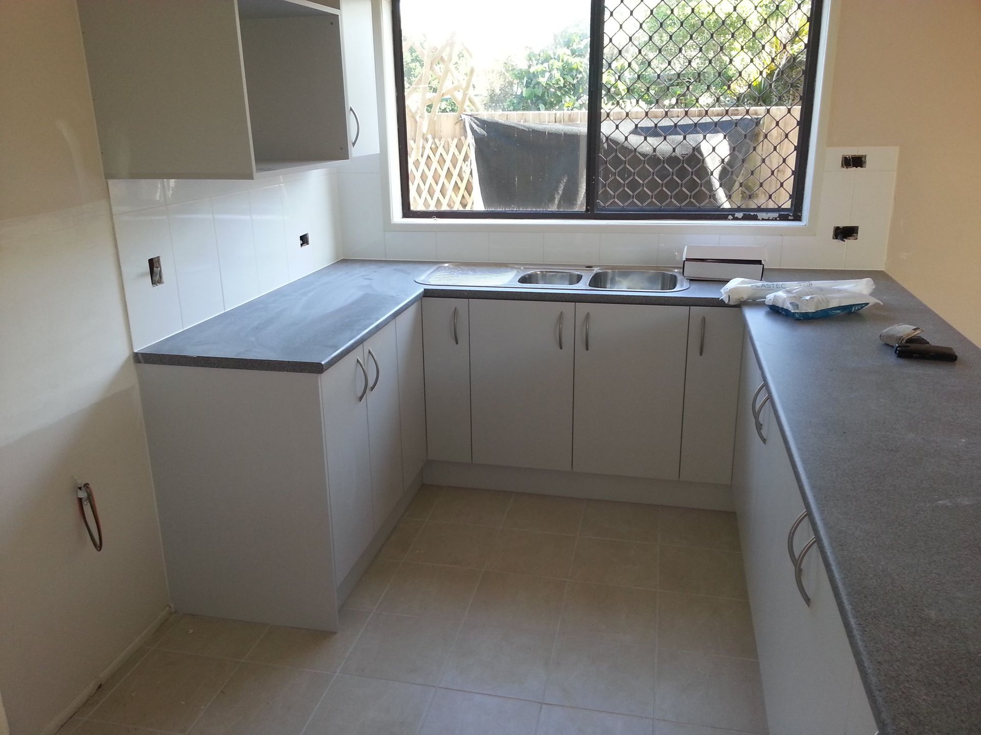 An Empty Kitchen With White Cabinets and a Sink — Suncoast Kitchens In Maroochydore, QLD