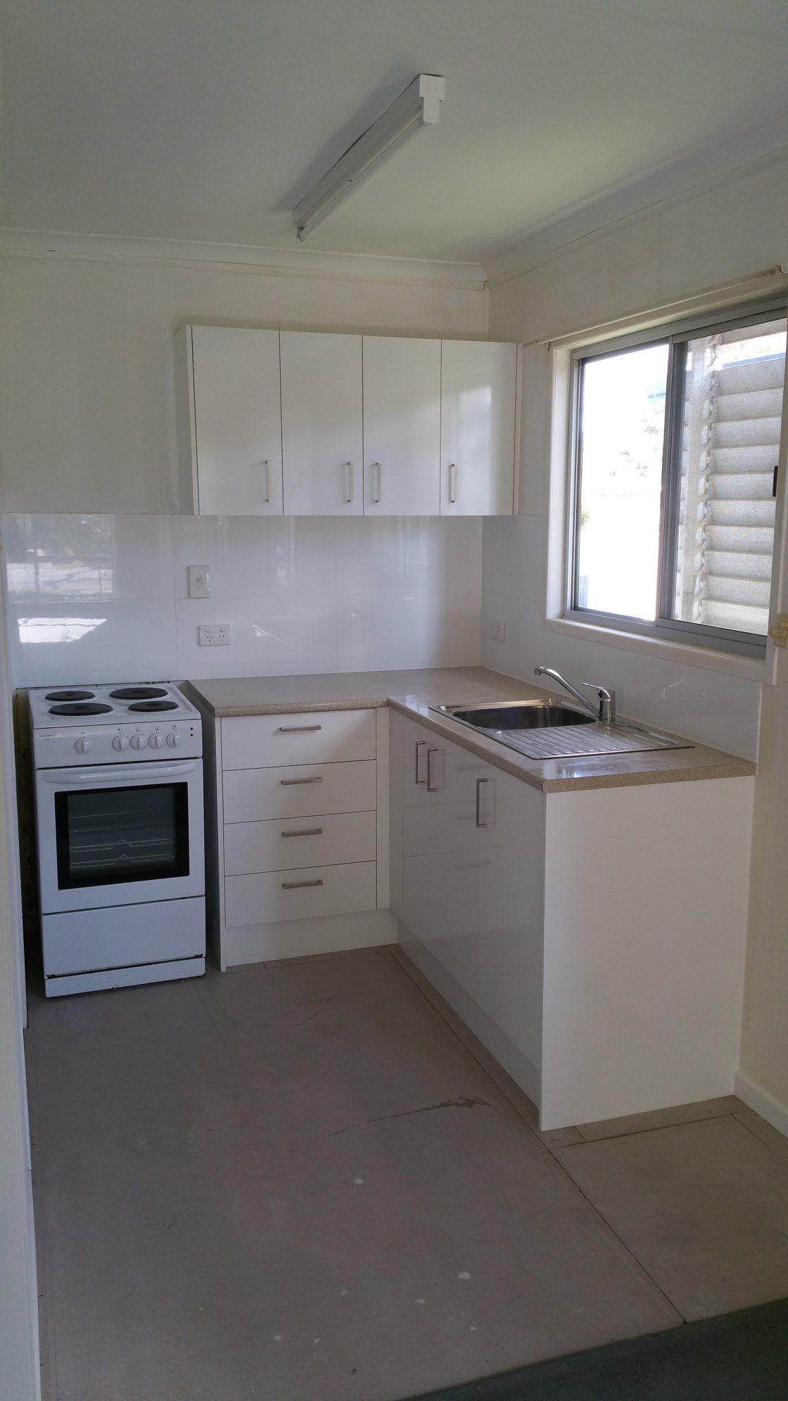 A Kitchen With White Cabinets, a Stove, a Sink and a Window — Suncoast Kitchens In Kunda Park, QLD