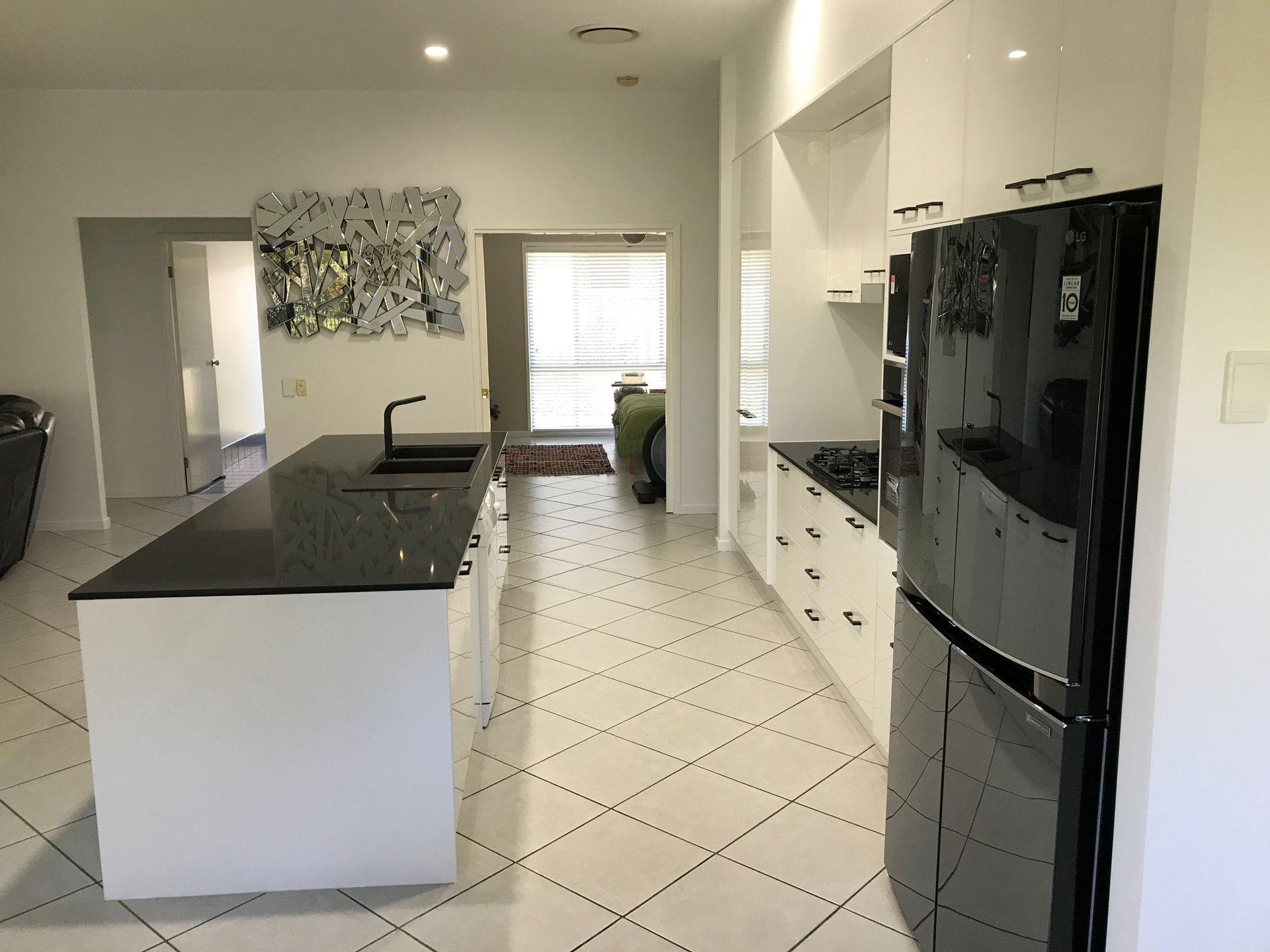 A Kitchen With White Cabinets and a Black Refrigerator — Suncoast Kitchens In Noosa, QLD