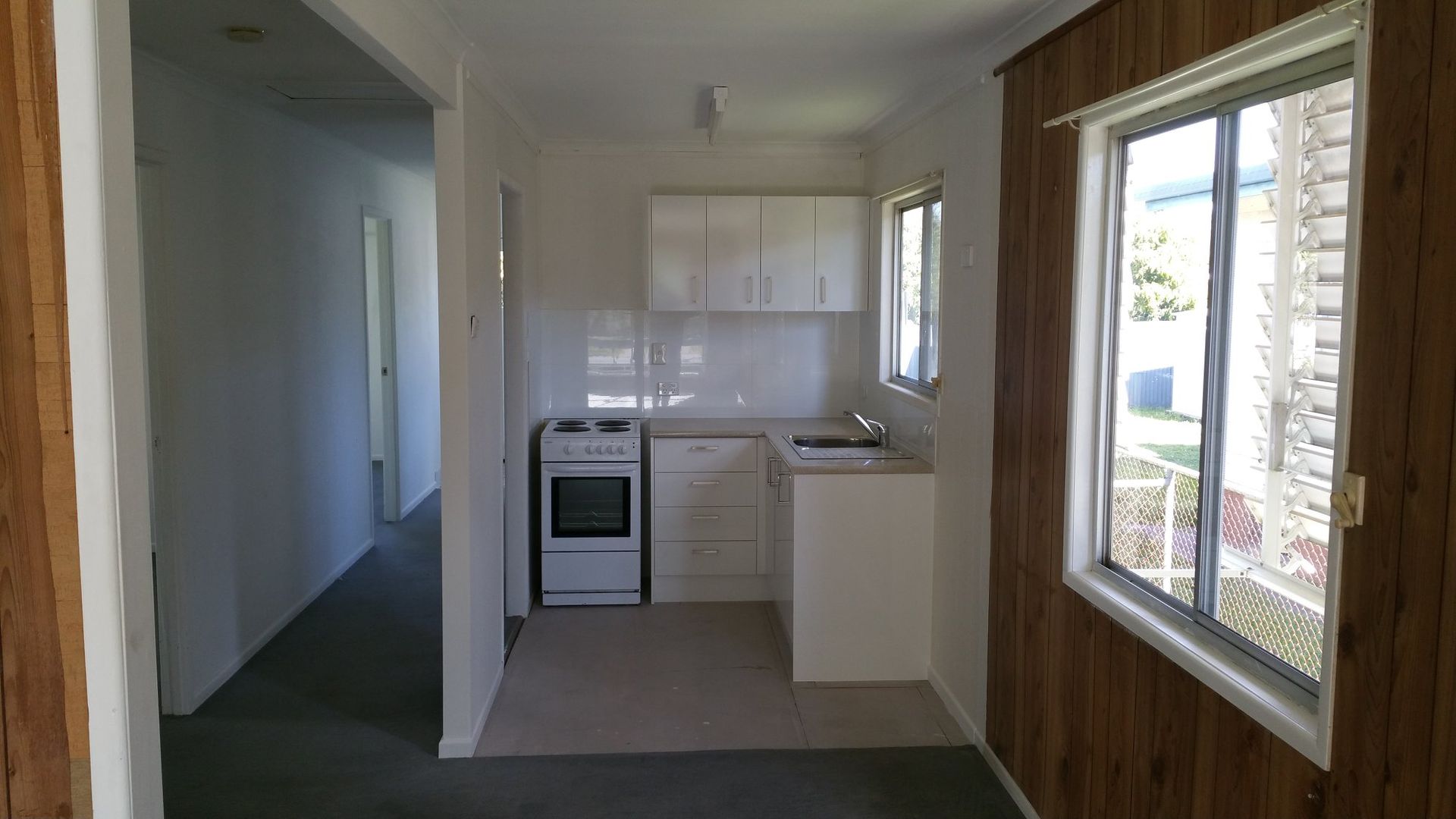 An Empty Kitchen With a Stove, Sink, and Window — Suncoast Kitchens In Kunda Park, QLD