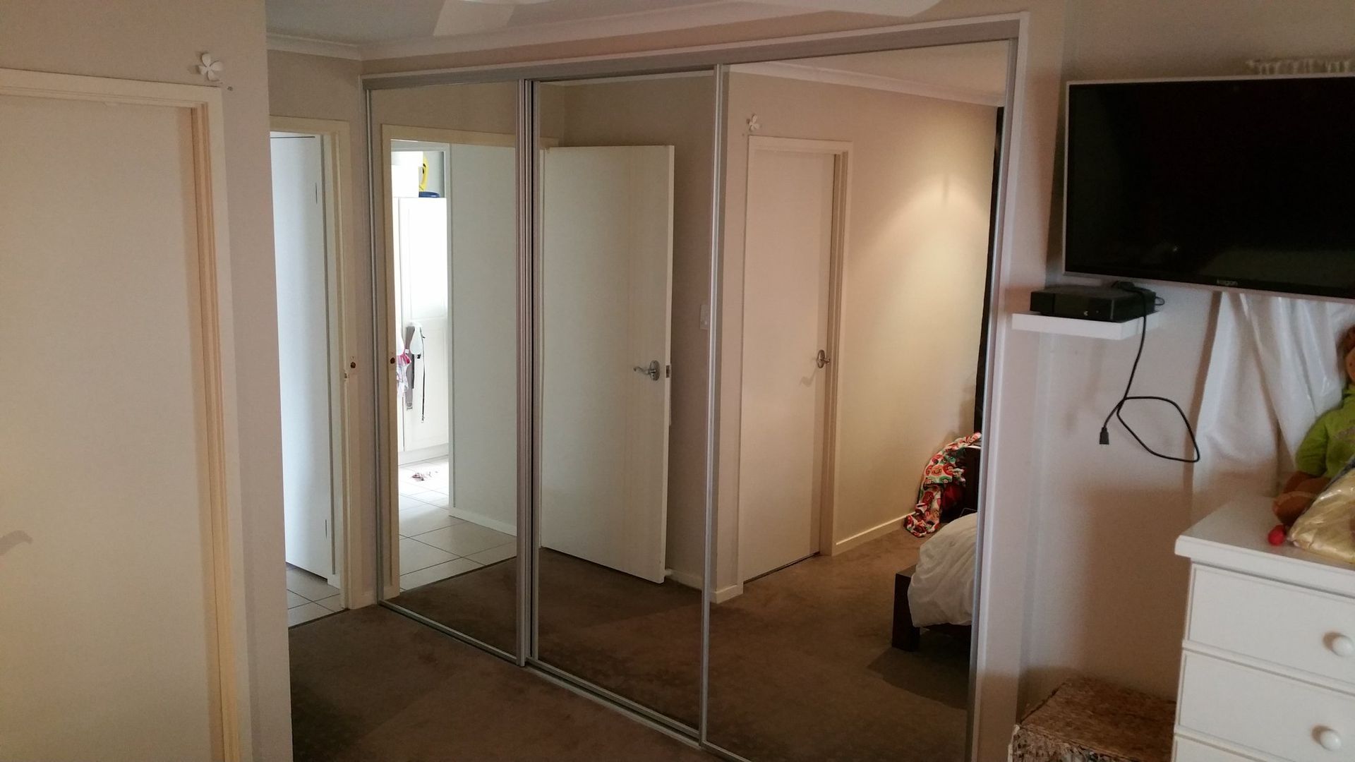 A Bedroom With Sliding Glass Doors and a Flat Screen Tv — Suncoast Kitchens In Kunda Park, QLD