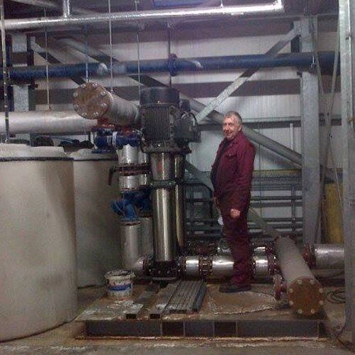 A man stands in a factory next to machinery