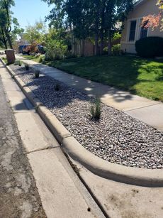 A sidewalk with gravel on the side of it and a house in the background.
