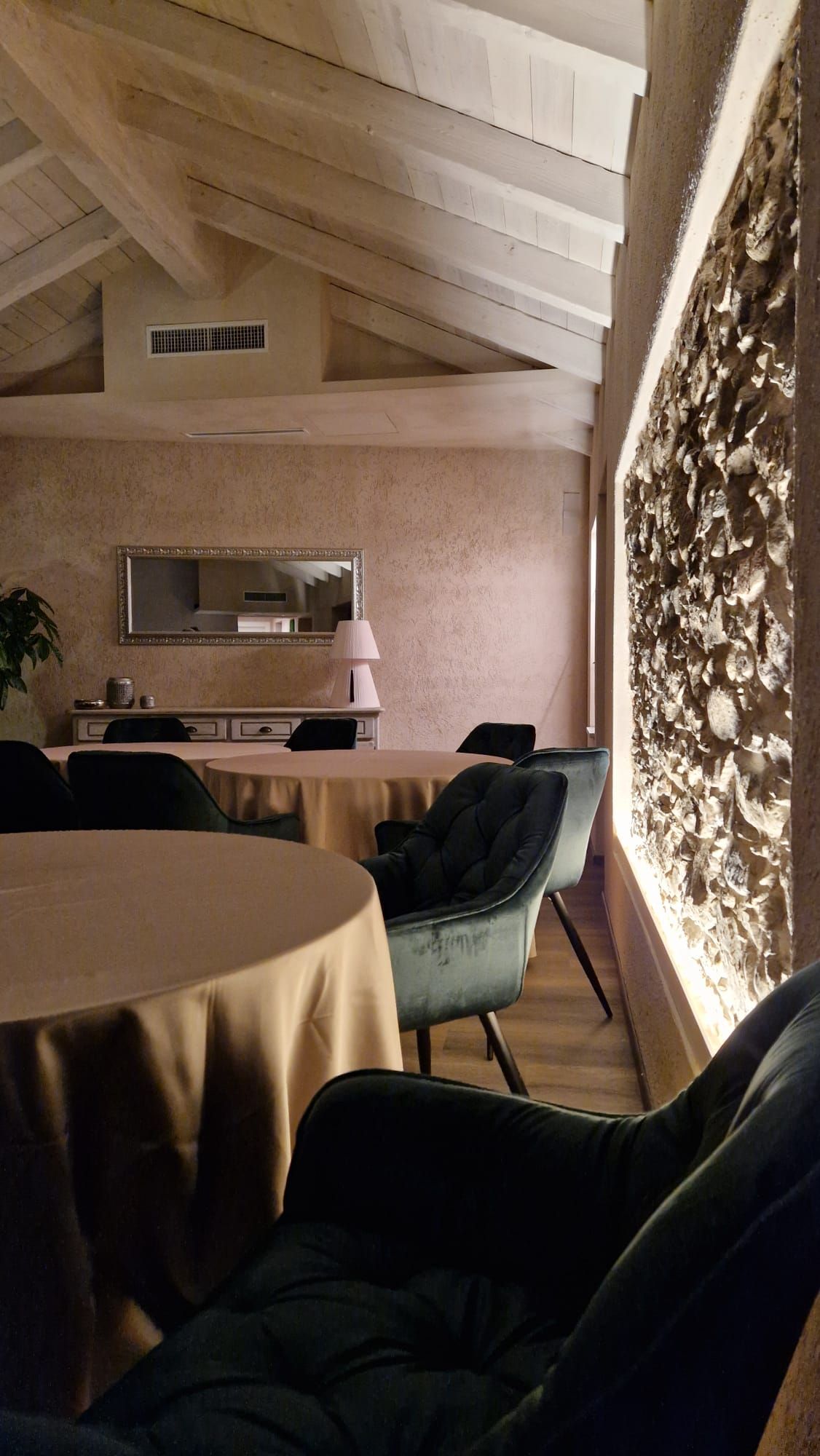 Una stanza con tavoli e sedie e un muro di pietra