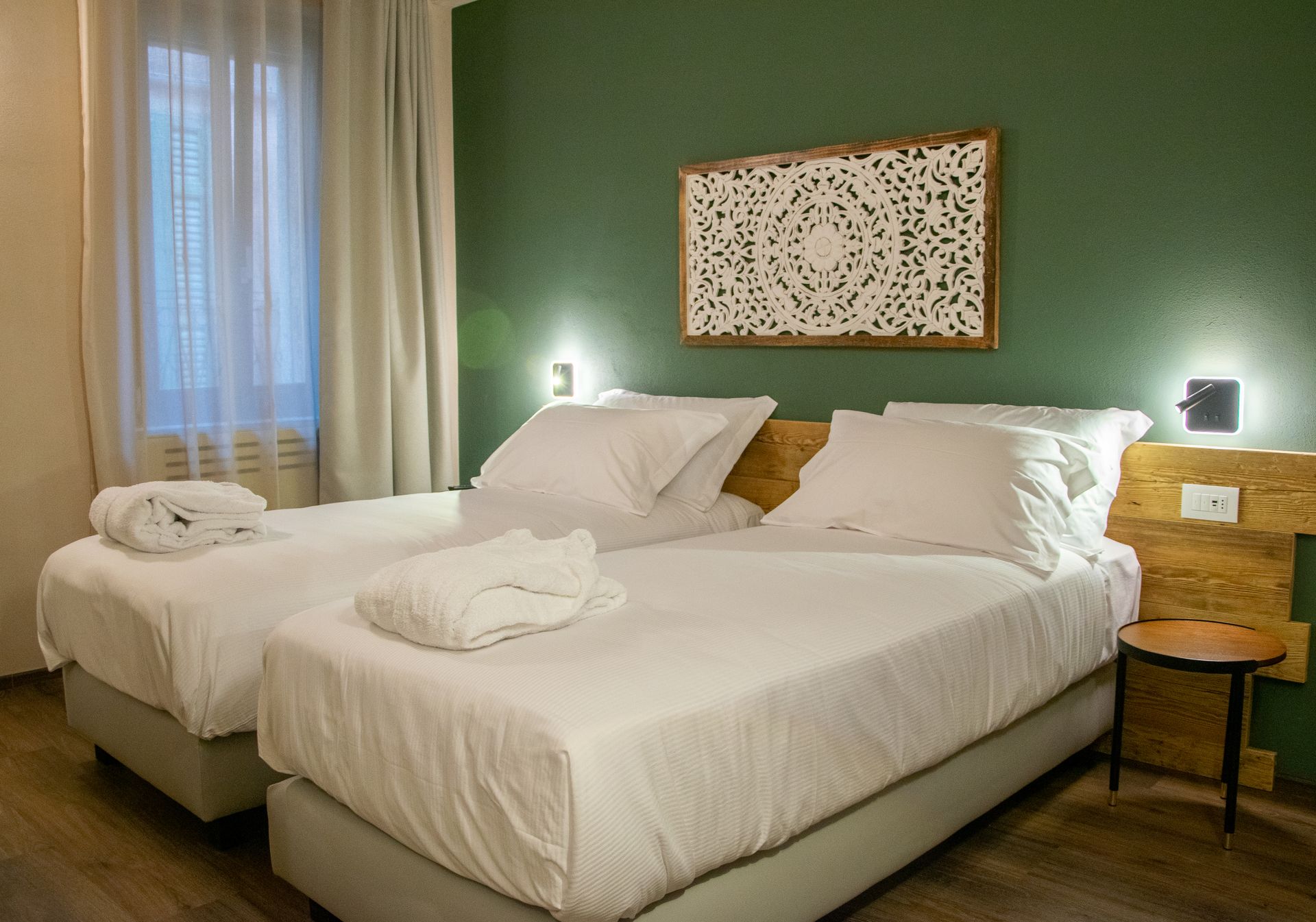 Una stanza d'albergo con due letti e una parete verde.