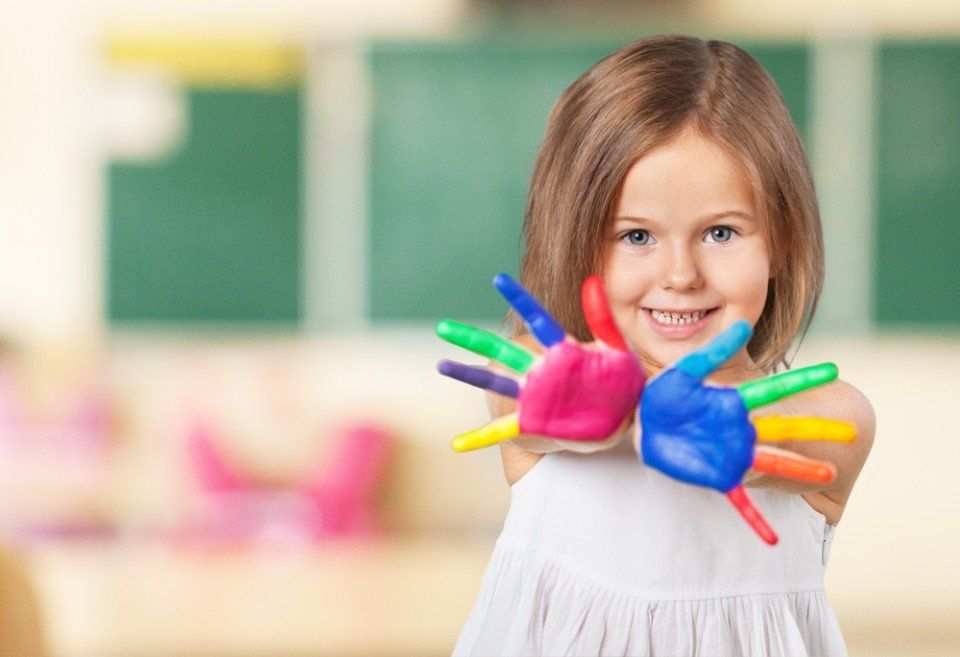 una bambina con le mani colorate di pittura