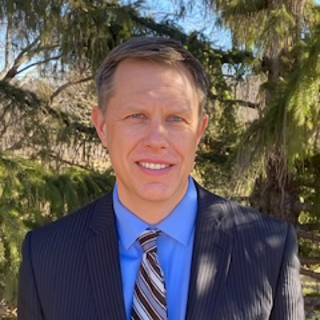 A man in a suit and tie is smiling for the camera.