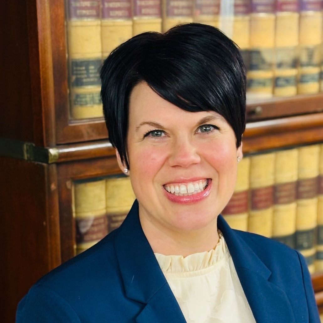 A woman in a tan jacket is smiling for the camera.