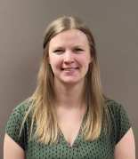 A woman in a green shirt is smiling for the camera.