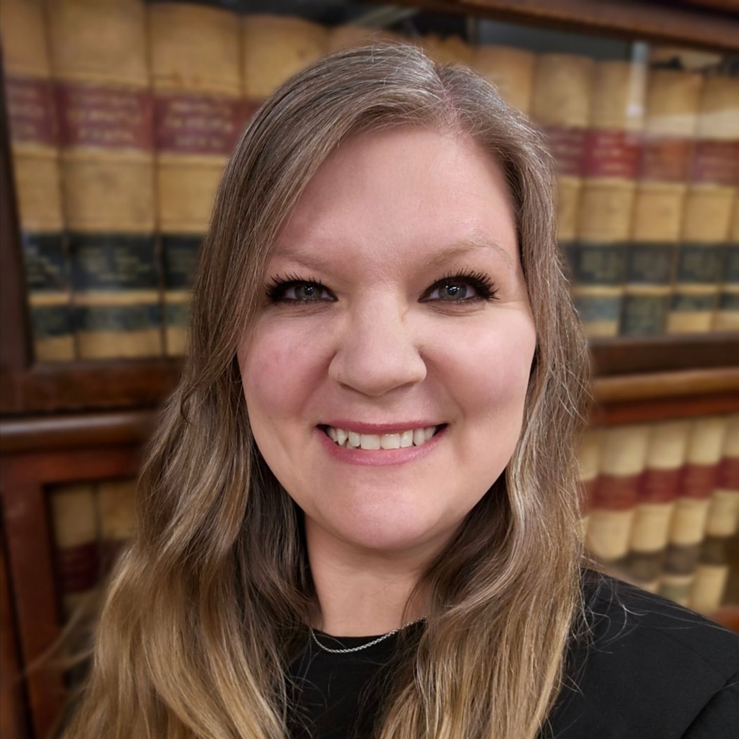 A woman with long blonde hair and a tattoo on her chest is smiling for the camera.