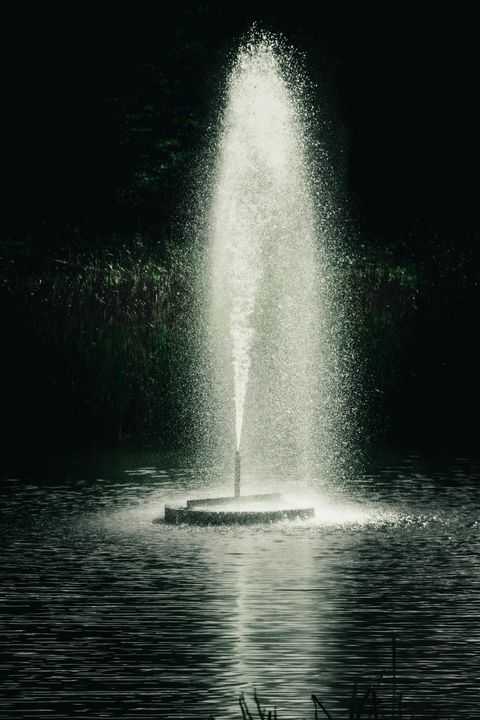A fountain is spraying water into a lake at night.