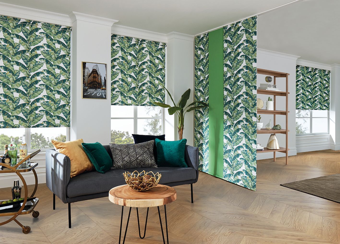 Living room with tropical leaf print blinds and wallpaper. Sofa with colorful pillows, wooden table.  Abundance Blinds In Charmhaven, NSW