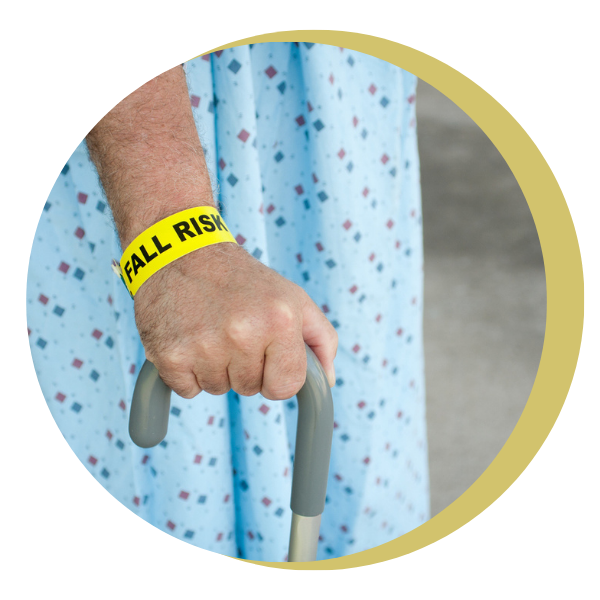 A person wearing a fall risk wristband is holding a cane