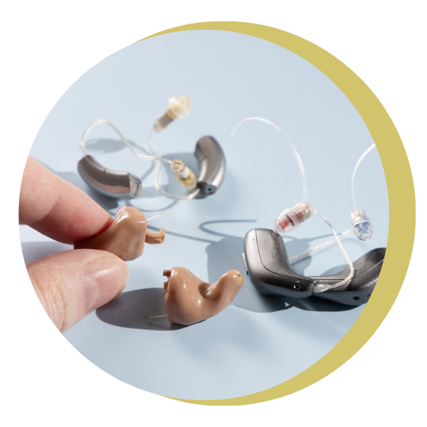 A person is holding a pair of hearing aids in their hand
