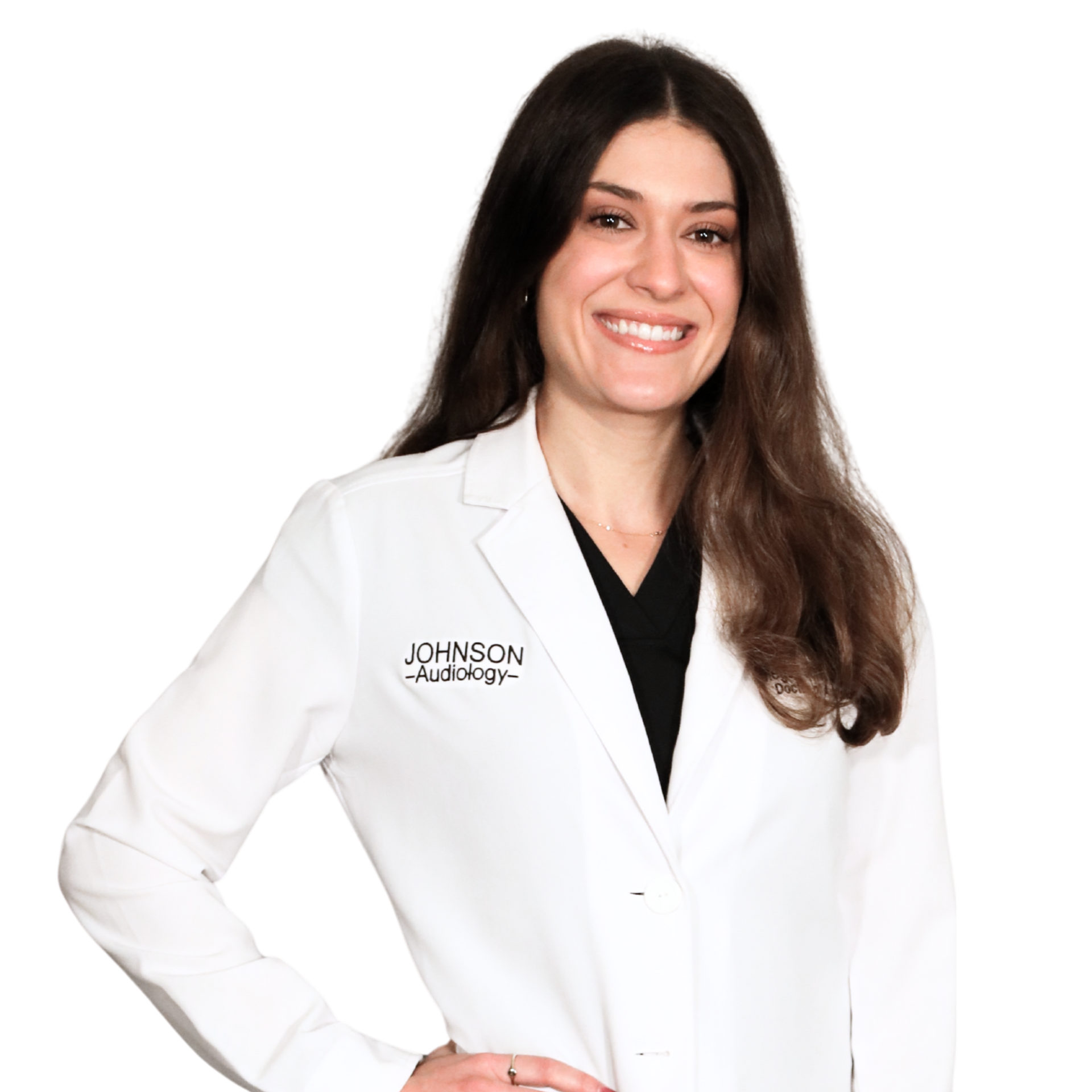 Woman in white lab coat smiles, standing with hand on hip;