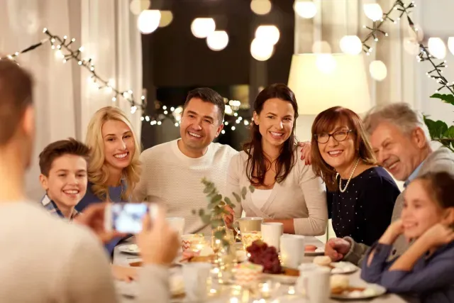 A man is taking a picture of his family at a dinner table.
