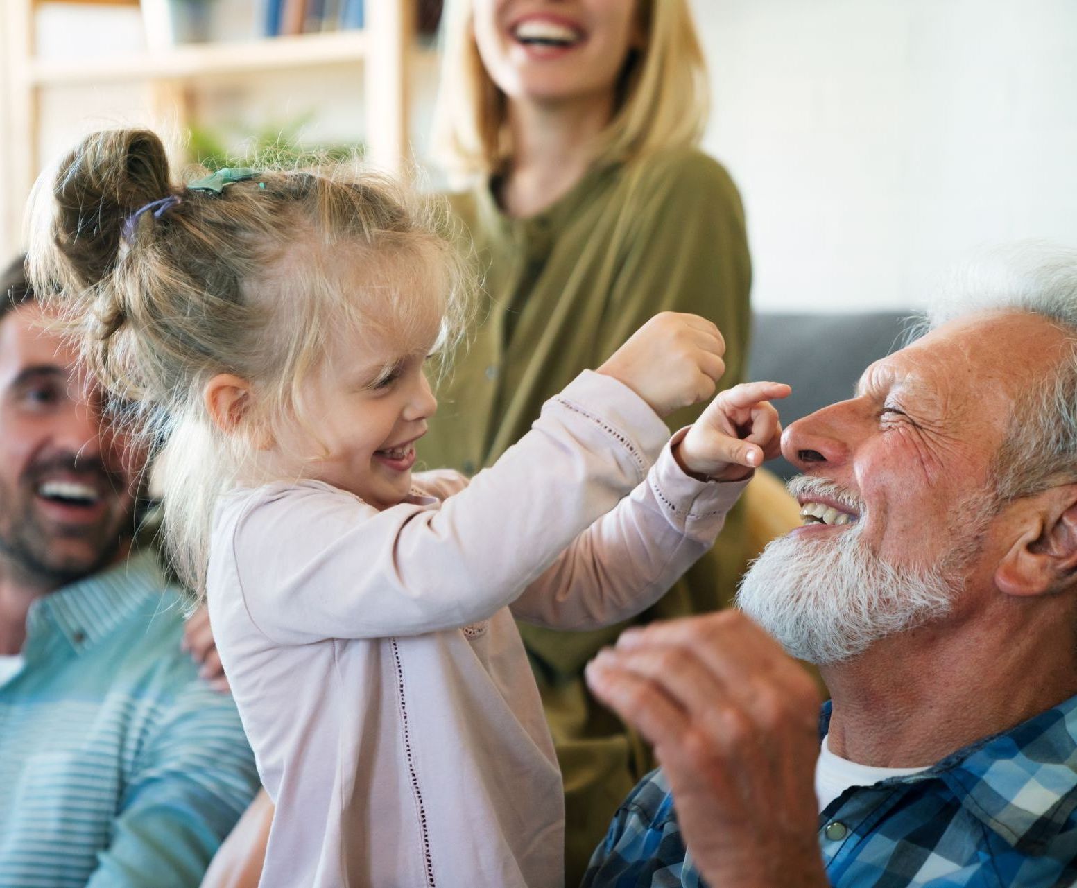 A little girl is playing with an older man in a living room.