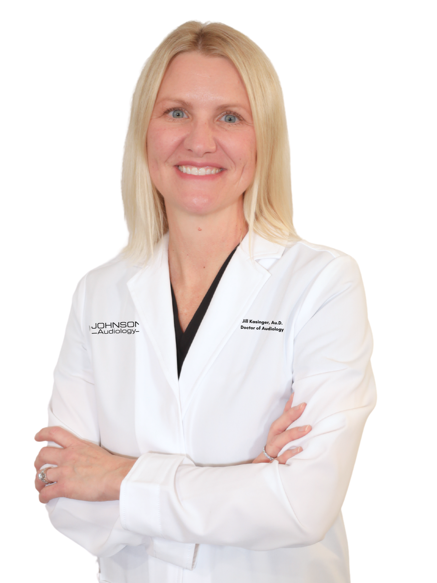 A woman in a white lab coat is smiling and holding an otoscope