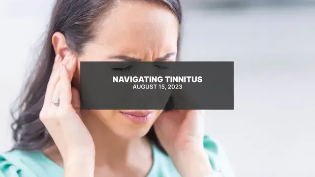 A woman is holding her ears because she has a headache.