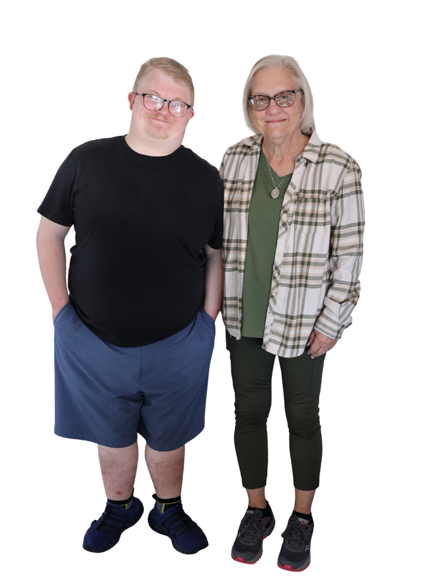 A person with glasses wearing a black shirt and blue shorts and a woman wearing a plaid shirt and green leggings, both smiling.