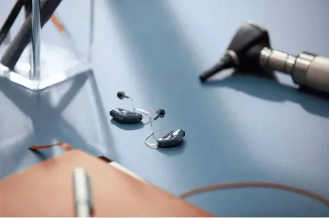 A pair of hearing aids are sitting on a table next to a stethoscope.