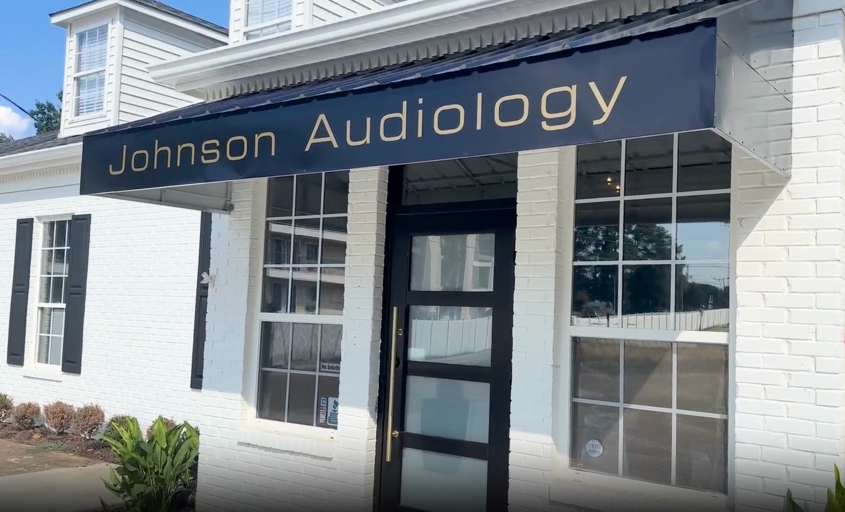 Johnson Audiology clinic with black awning and gold lettering, white building.