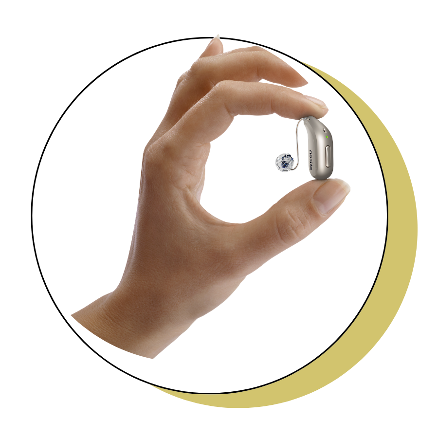 A person is holding a pair of hearing aids in their hand