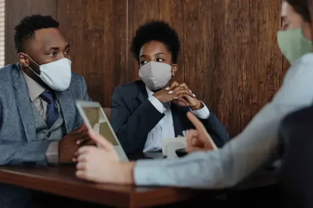 A group of people wearing face masks are sitting at a table.