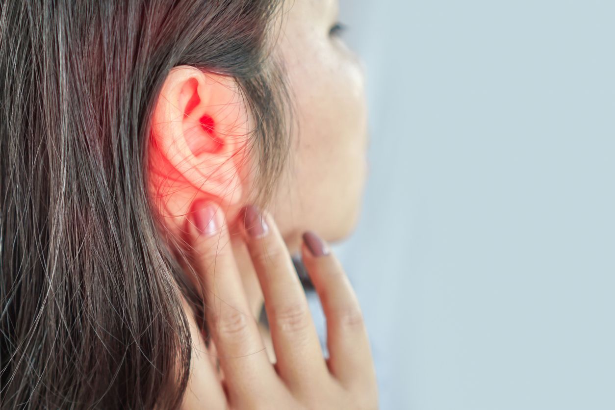 A woman is holding her ear in pain.