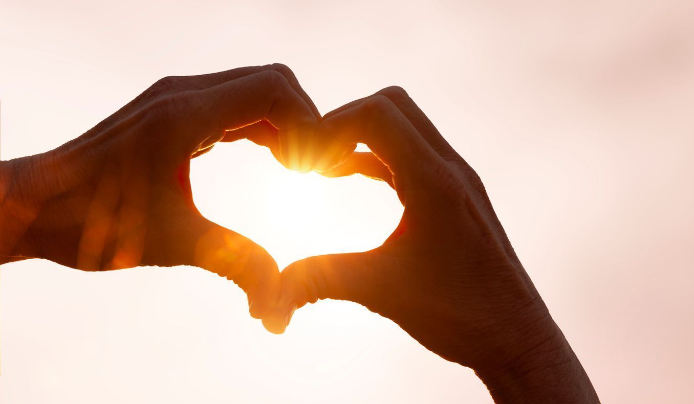 A person is making a heart shape with their hands.