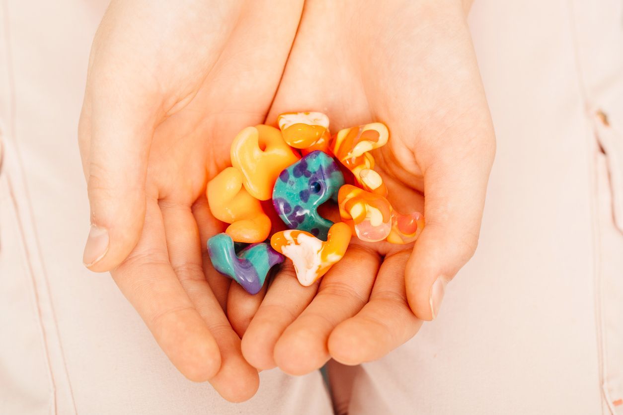 A person is holding a bunch of colorful ear plugs in their hands.